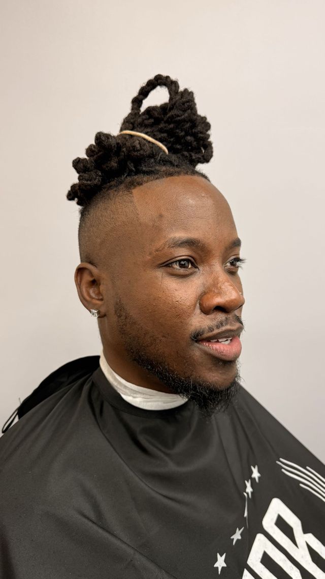 High fade with locs styled into a top knot